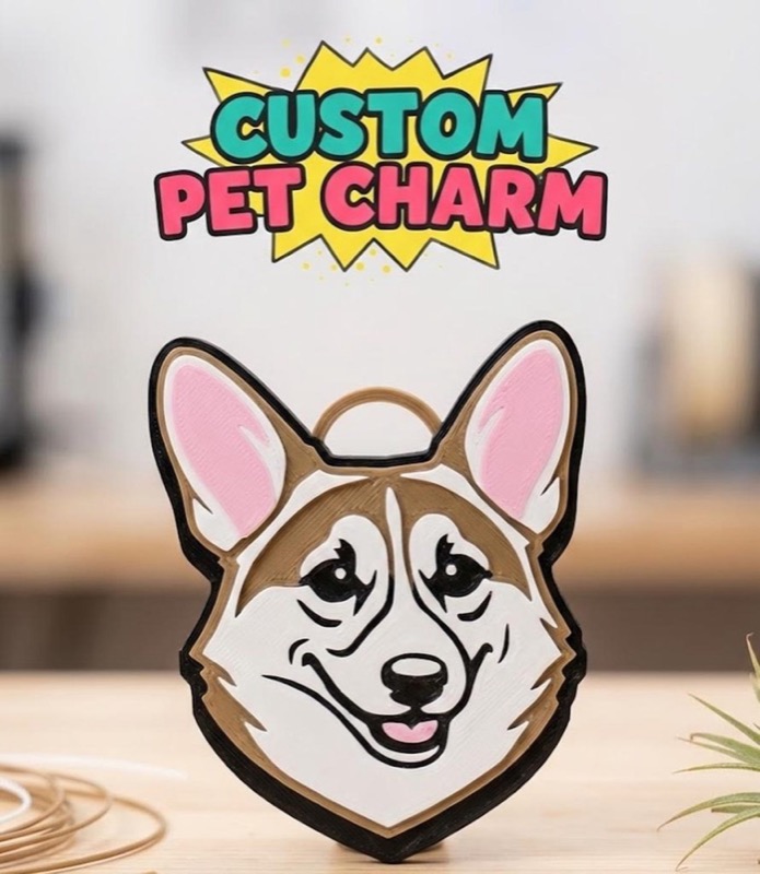 A custom pet charm featuring a smiling corgi face with pink ears, brown and white fur, and a black outline.