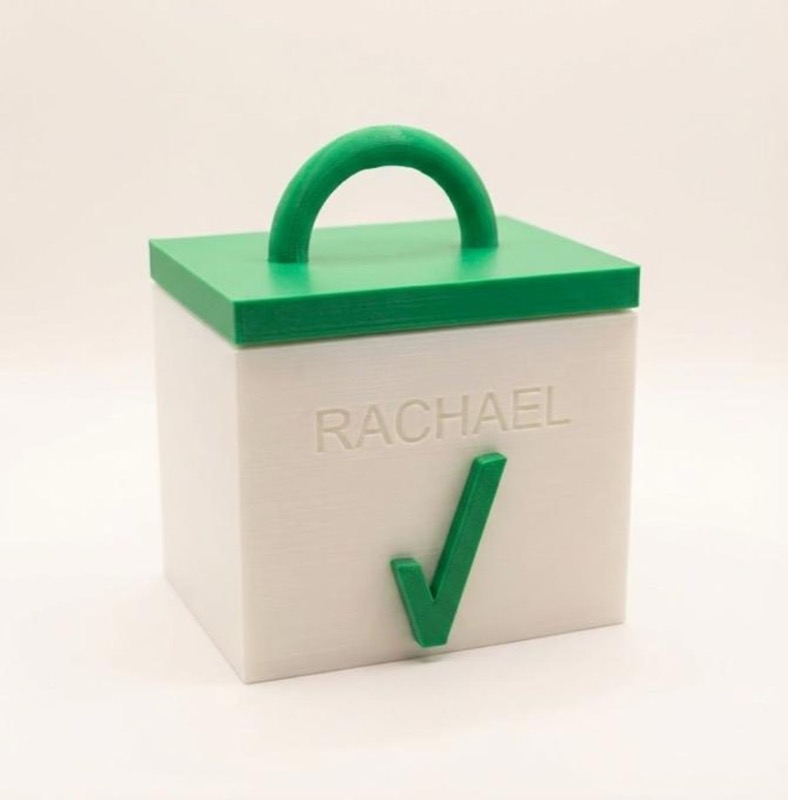 A white square box with a green lid and handle.